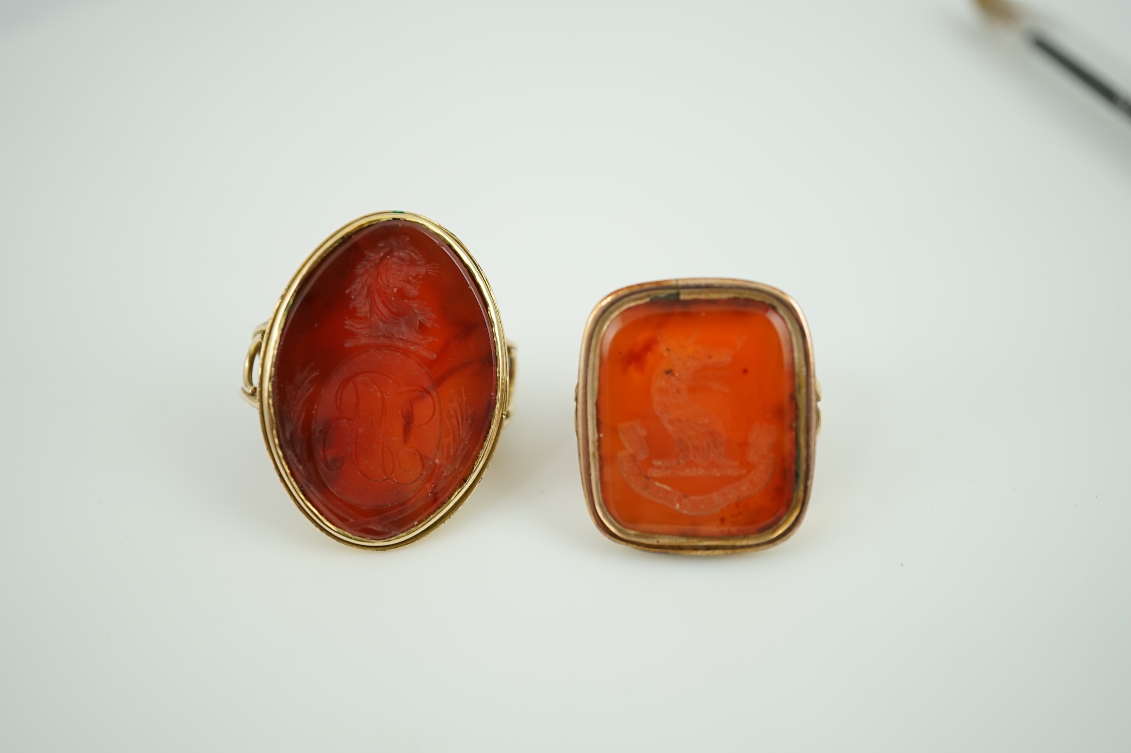 Two Victorian yellow metal and agate set intaglio rings, both matrix carved with a crest, one with monogram also, sizes K and L, gross weight 21.5 grams.